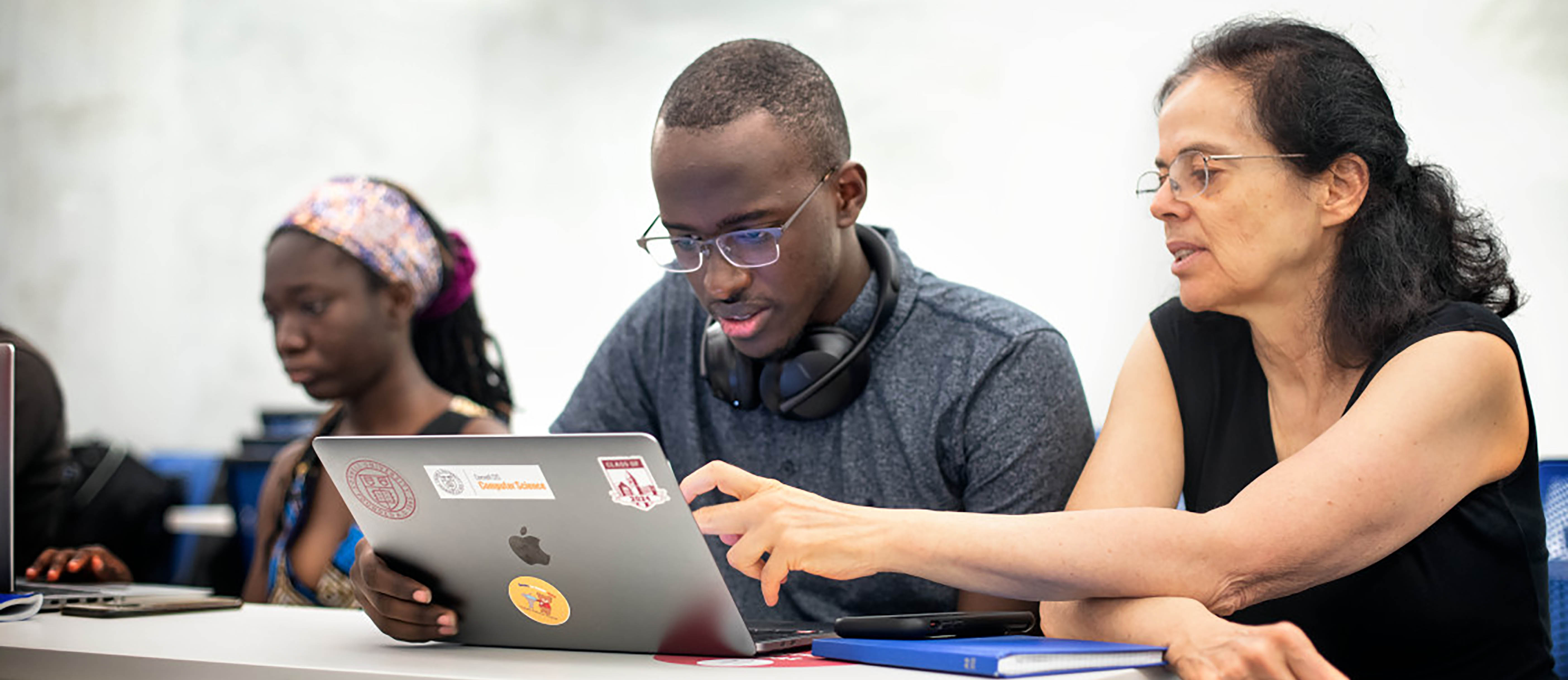 Student and faculty member discuss work together over a laptop in class