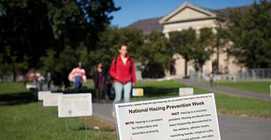 Student walks through an outdoor hazing prevention installation on the Arts Quad
