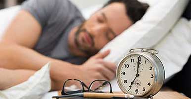 Man in bed next to alarm clock