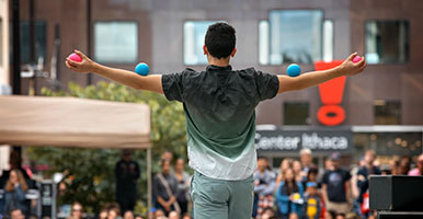 Student juggles in front of audience on the Ithaca Commons